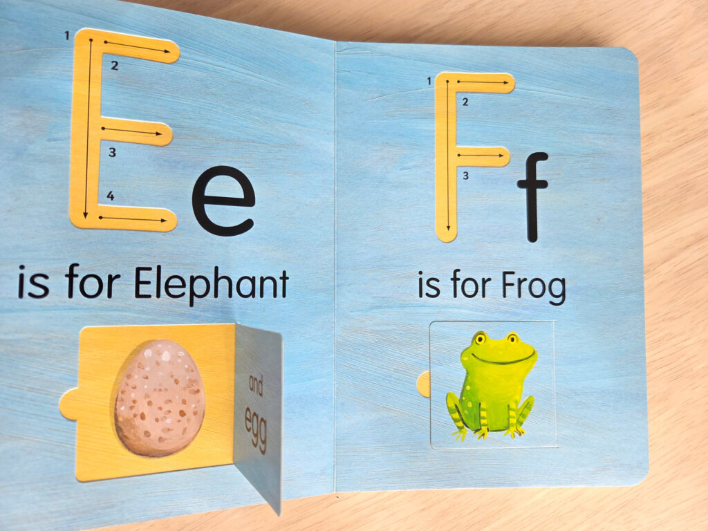 「Hello World! ABCs」のEとFのページ。左側のゾウのイラスト(扉)がめくられており、中から「and egg」という文字とともに、卵のイラストが現れている。1つの文字で2つの単語(Elephantとegg)が学べる仕掛けが示されている。右側のカエルの扉は閉じている。